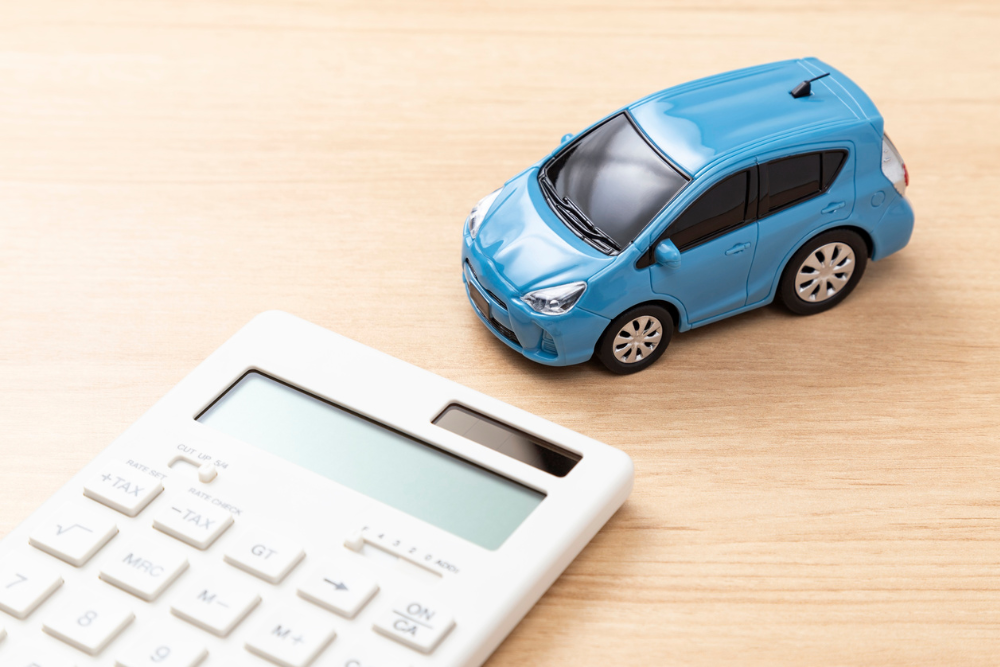 Calculator beside a small car model as someone calculates the value of a car and figures out how to sell their spouse’s car after their spouse dies.