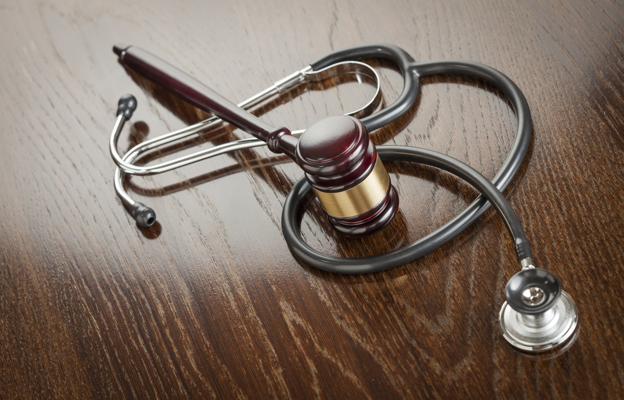 Medicaid Lawyer Warwick, RI - Gavel and Stethoscope on Reflective Wooden Table.