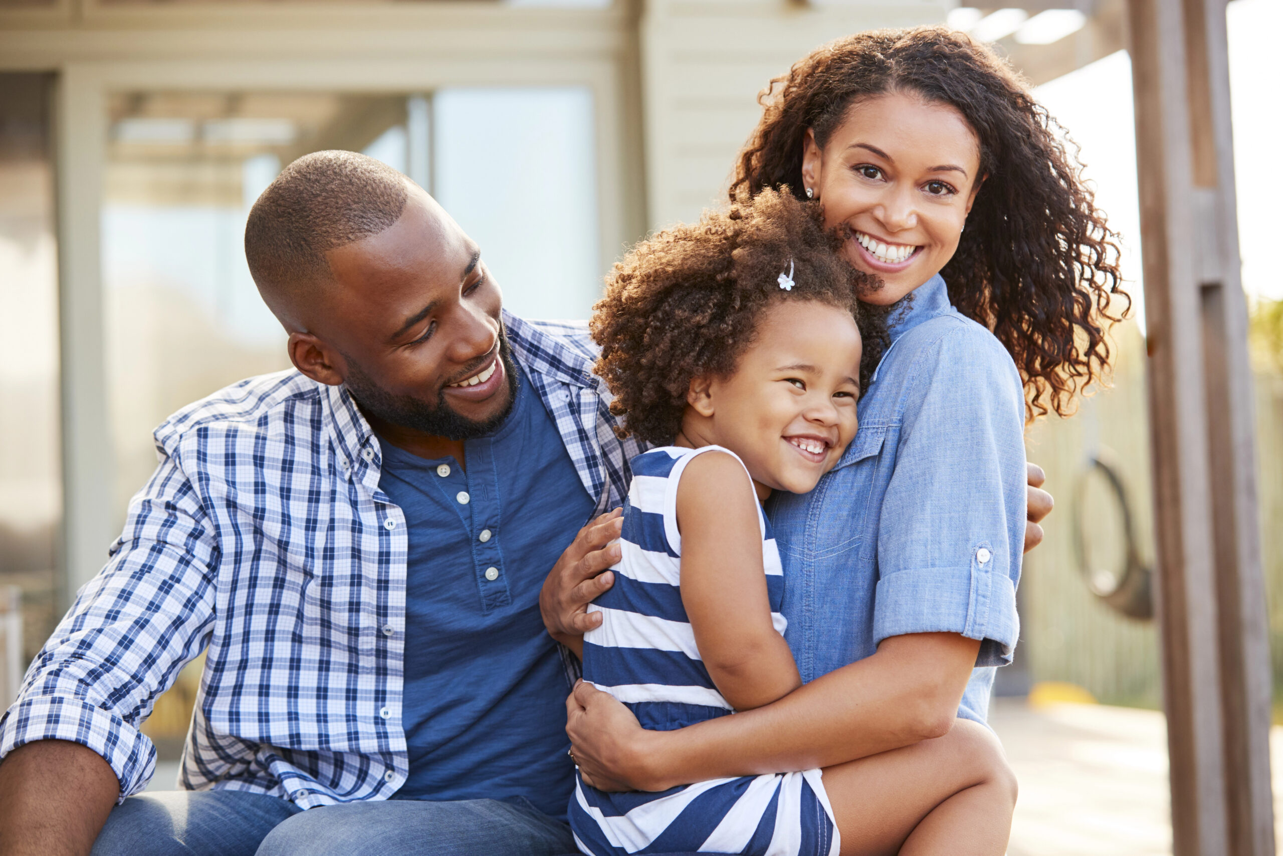 African-American family smiling in front of house