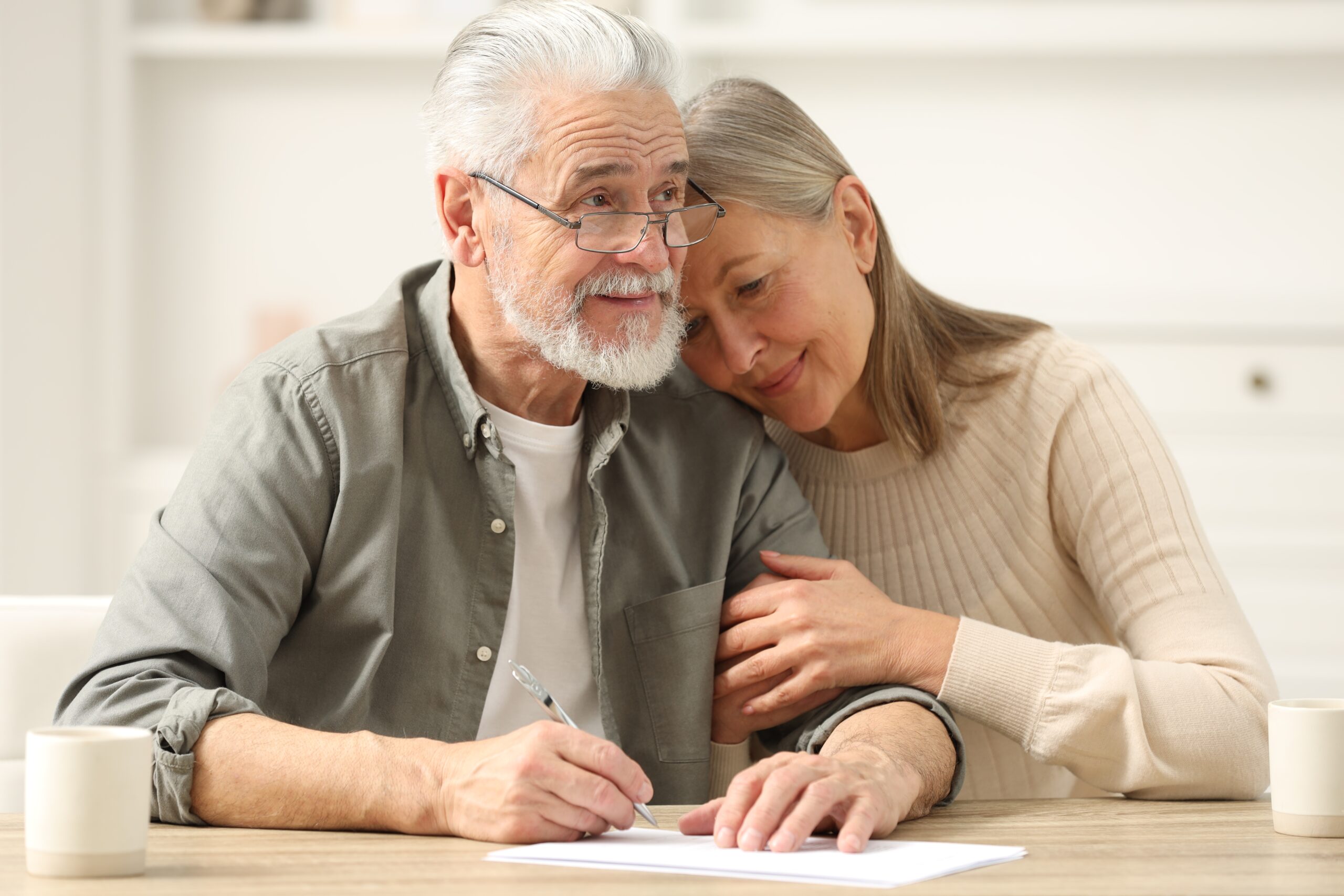 Senior couple signing Last Will and Testament indoors